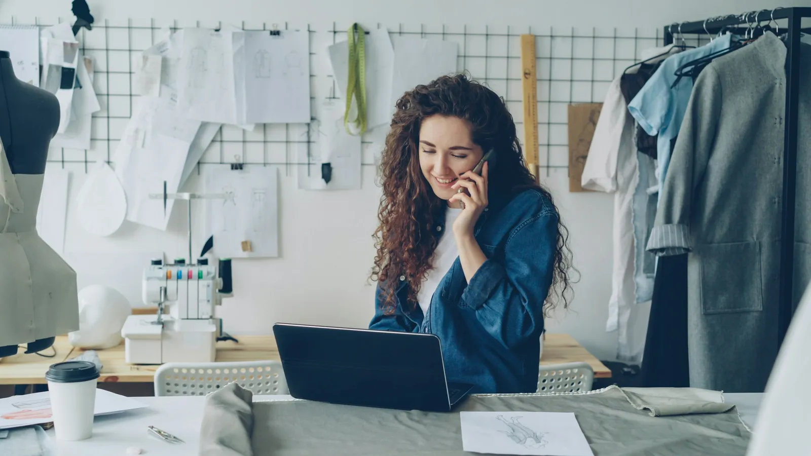 Clothing studio owner on the phone while working on a laptop