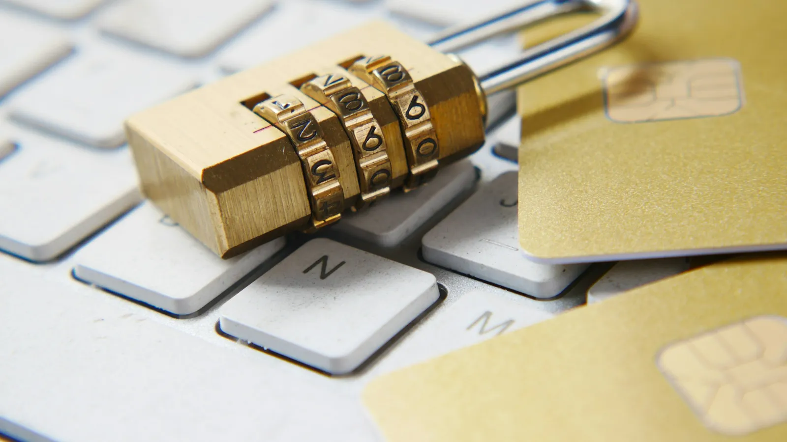 Combination padlock on a laptop keyboard next to two chip cards